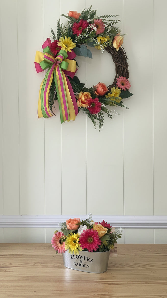 Bright Spring Garden Collection grapevine wreath hanging on wall and matching centerpiece displayed on a wooden table 
