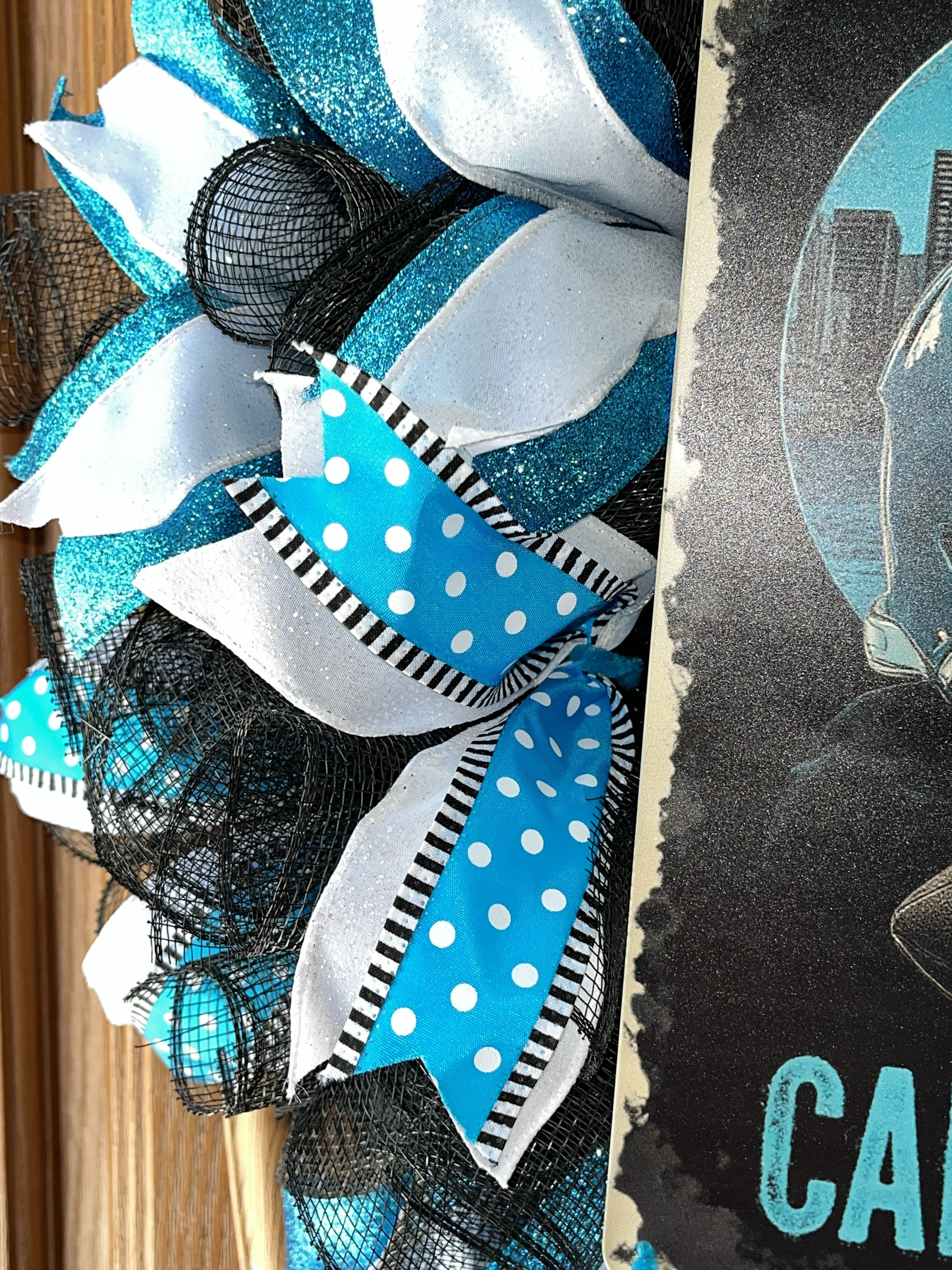 “Handmade Carolina football wreath featuring black, blue, and white mesh ribbon with a helmet and football sign, perfect for sports fan front door decor