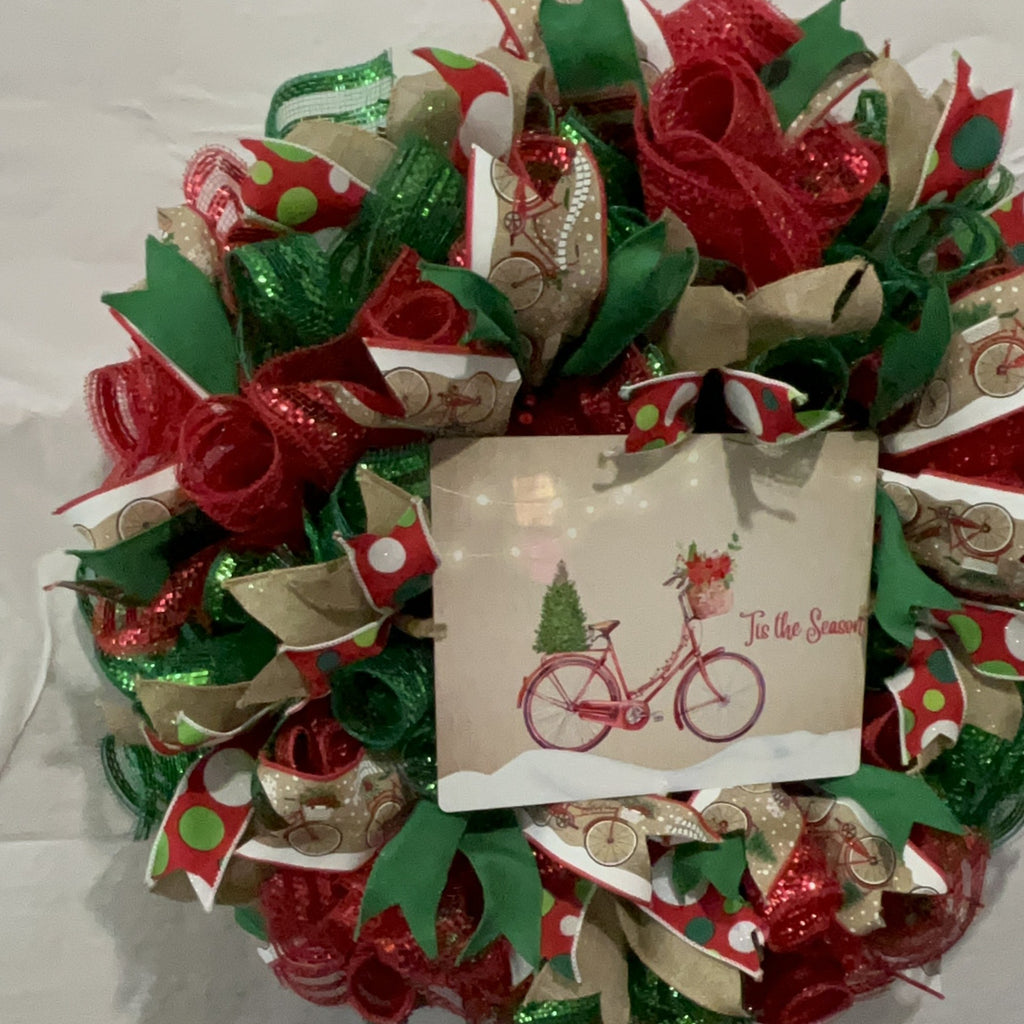 Handmade Christmas wreath with red and green mesh ribbon, featuring a vintage bicycle ‘Tis the Season’ sign for festive holiday front door decor.