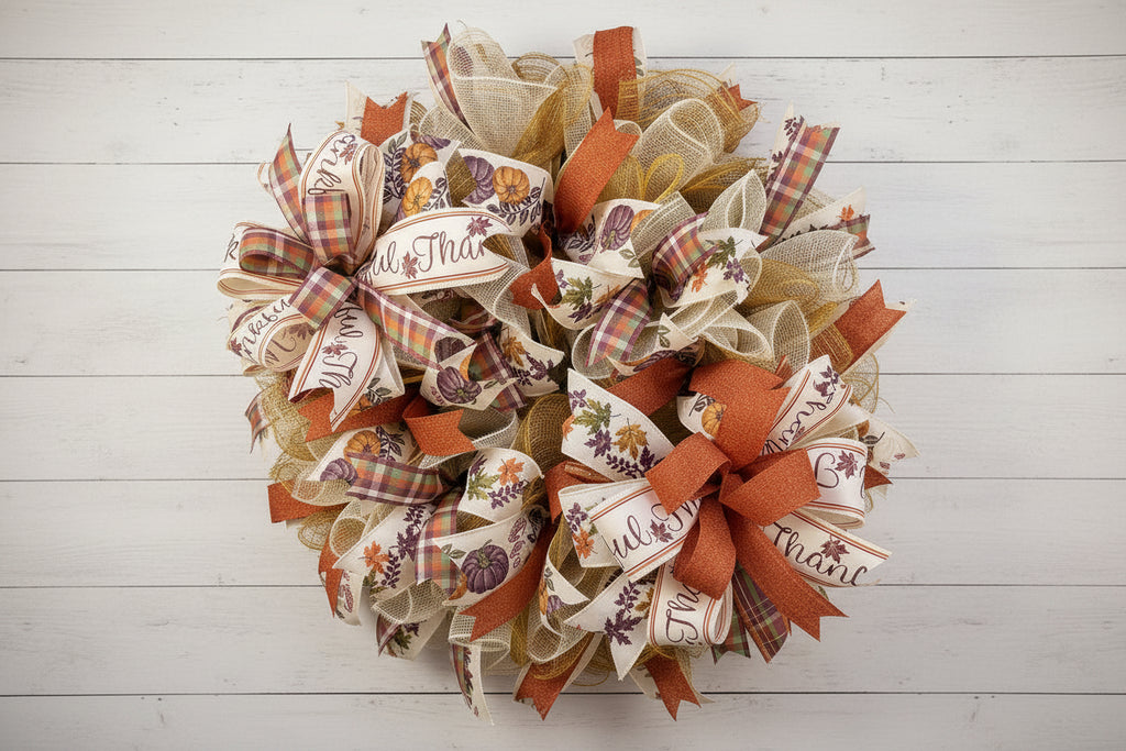 Handmade fall wreath with orange and gold mesh ribbon, featuring pumpkin and plaid accents with ‘Thankful’ wording for autumn front door decor.