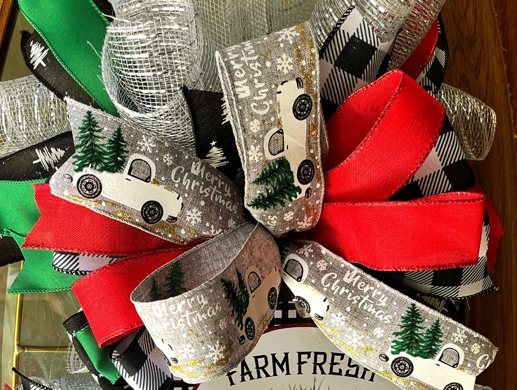 Handmade vertical Christmas swag featuring a vintage farmhouse truck with Christmas tree, accented with red, green, and buffalo check ribbon for front door decor.