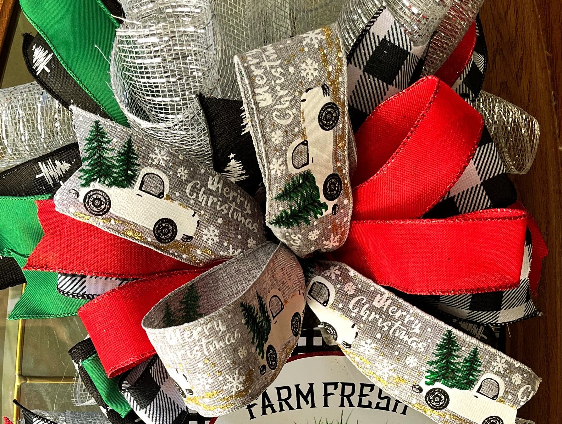 Handmade vertical Christmas swag featuring a vintage farmhouse truck with Christmas tree, accented with red, green, and buffalo check ribbon for front door decor.