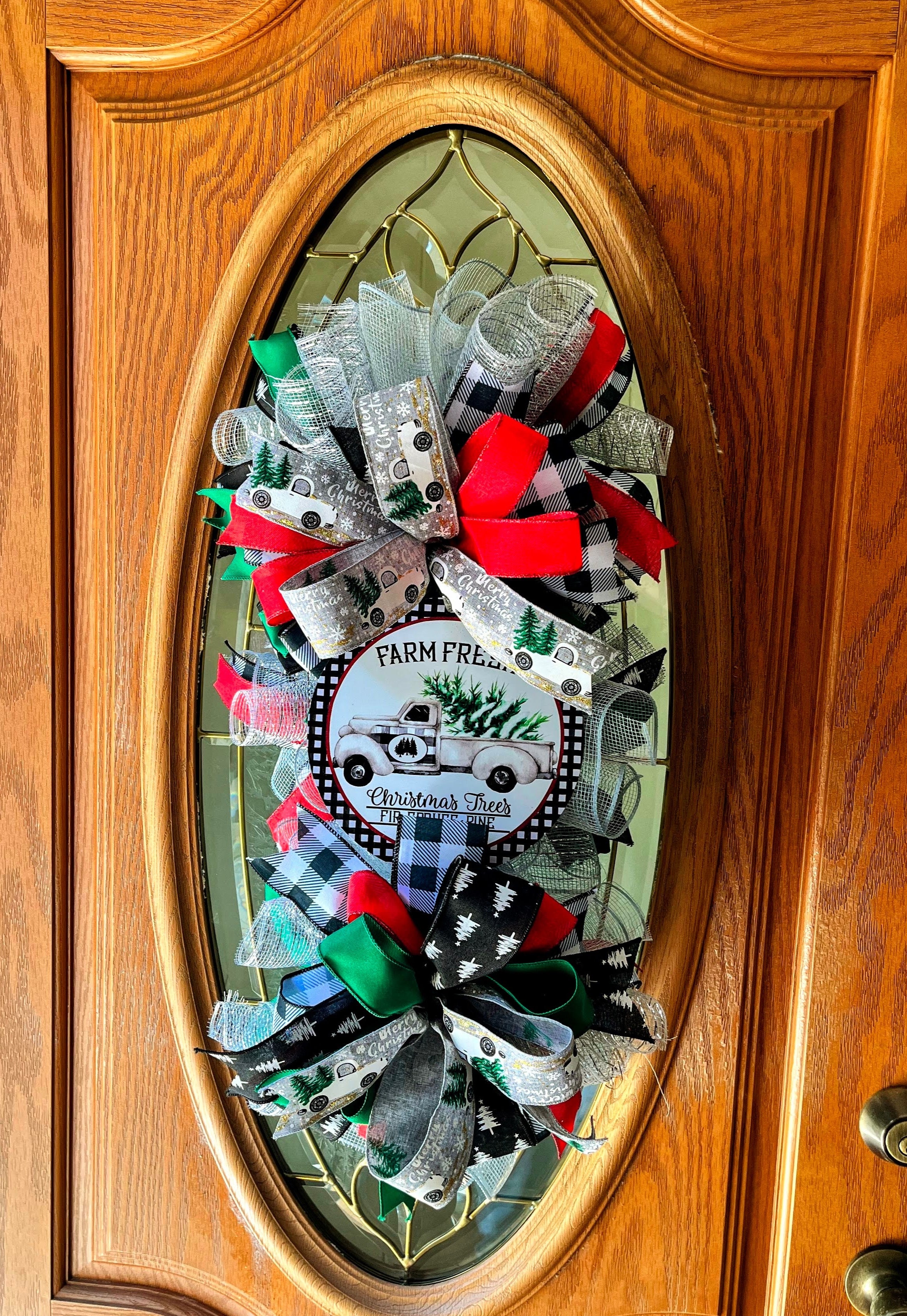 Handmade vertical Christmas swag featuring a vintage farmhouse truck with Christmas tree, accented with red, green, and buffalo check ribbon for front door decor.