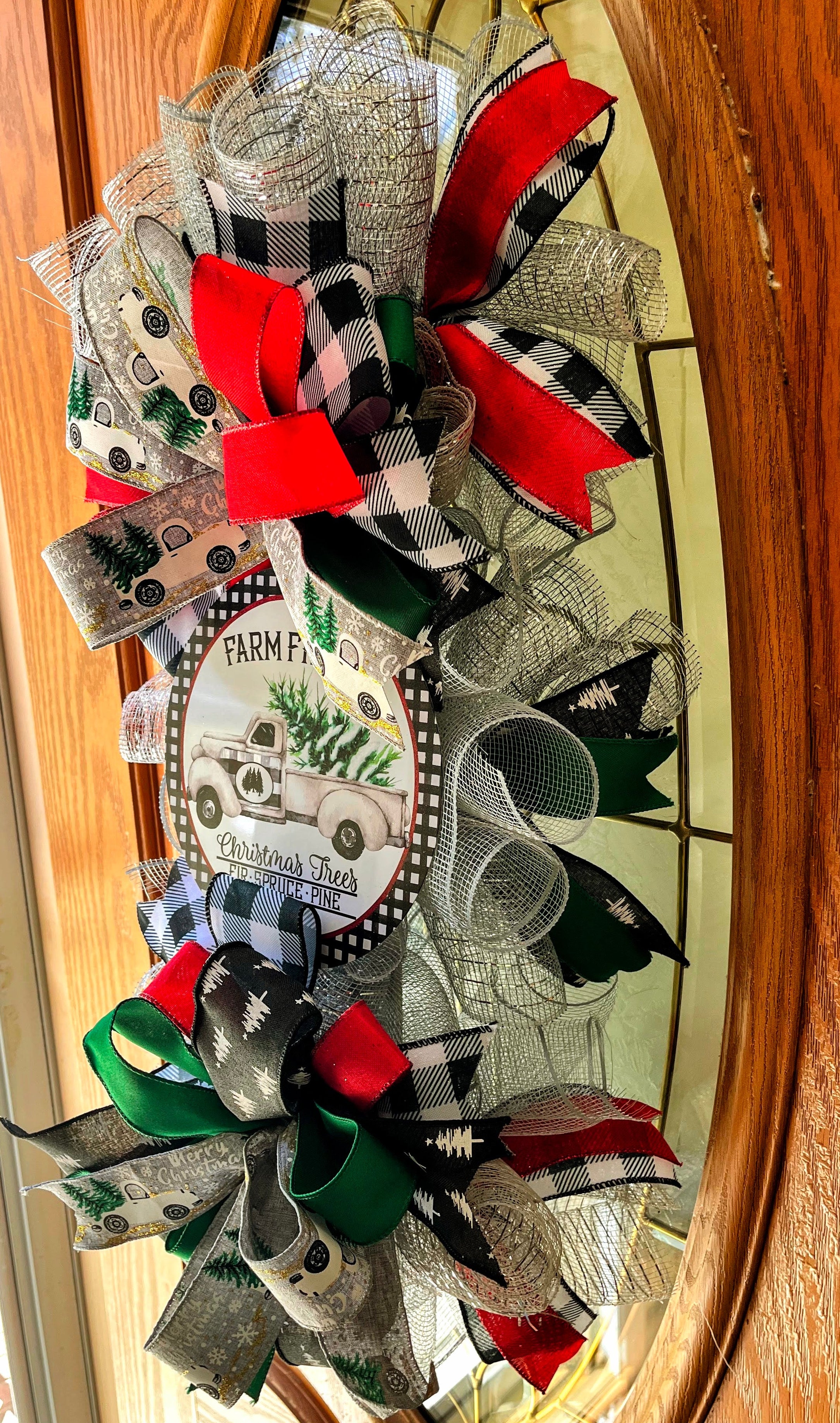 Handmade vertical Christmas swag featuring a vintage farmhouse truck with Christmas tree, accented with red, green, and buffalo check ribbon for front door decor.