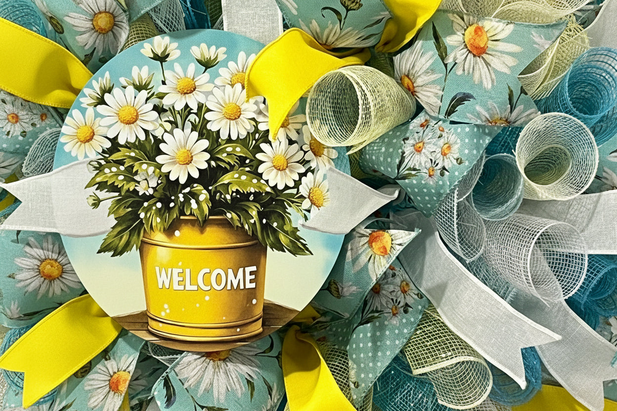 Handmade spring and summer wreath with blue and yellow mesh ribbon, featuring a daisy-filled welcome sign for cheerful front door decor.