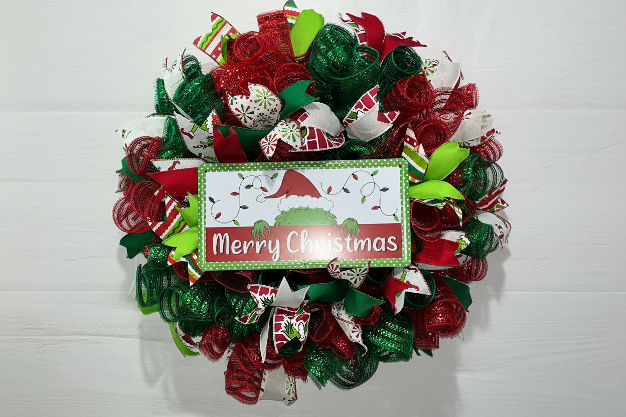 Handmade red and green Christmas wreath with a ‘Merry Christmas’ sign and whimsical Grinch-inspired design for festive front door decor.