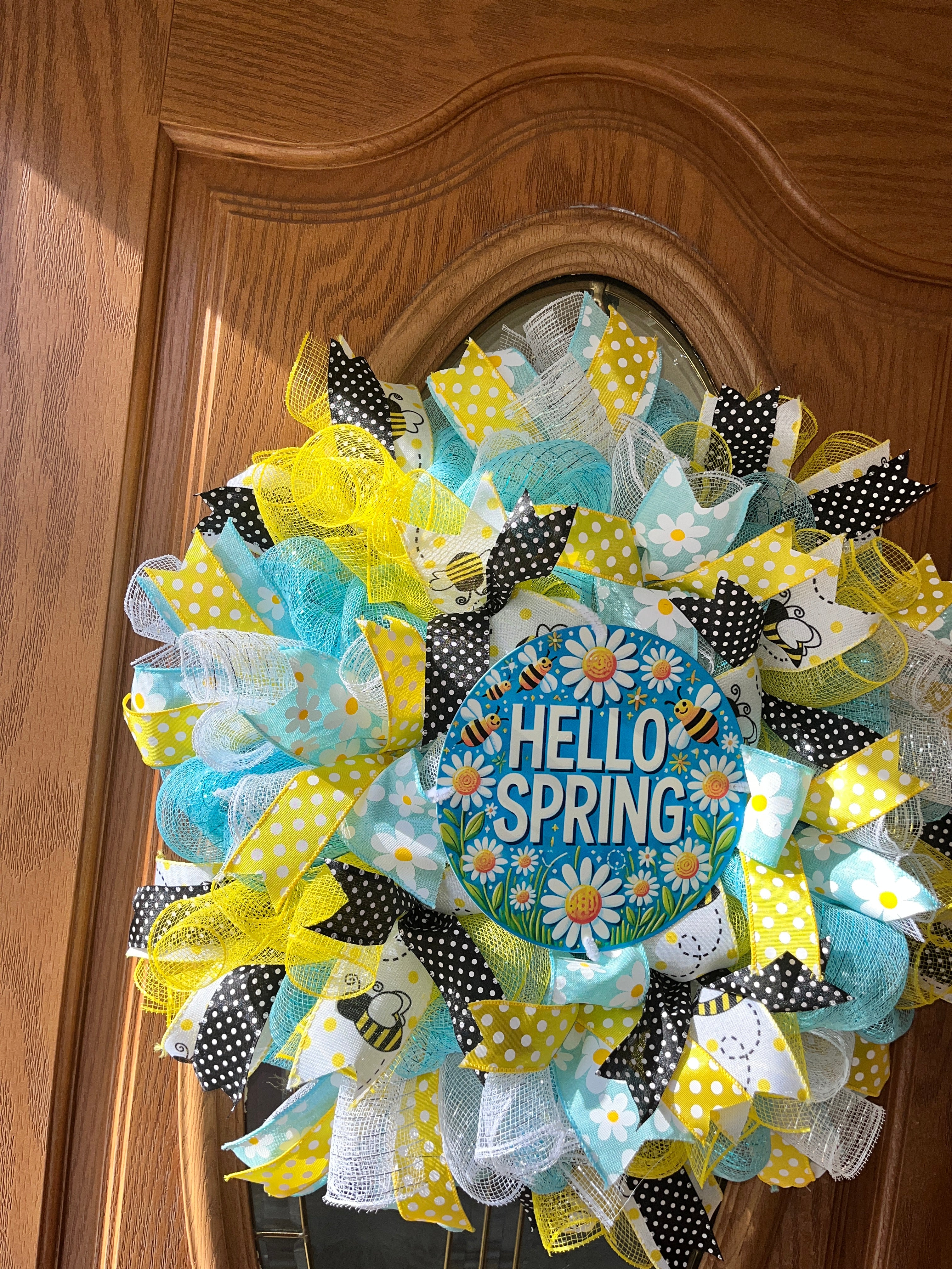 Decorative wreath with 'Hello Spring' sign on a wooden surface