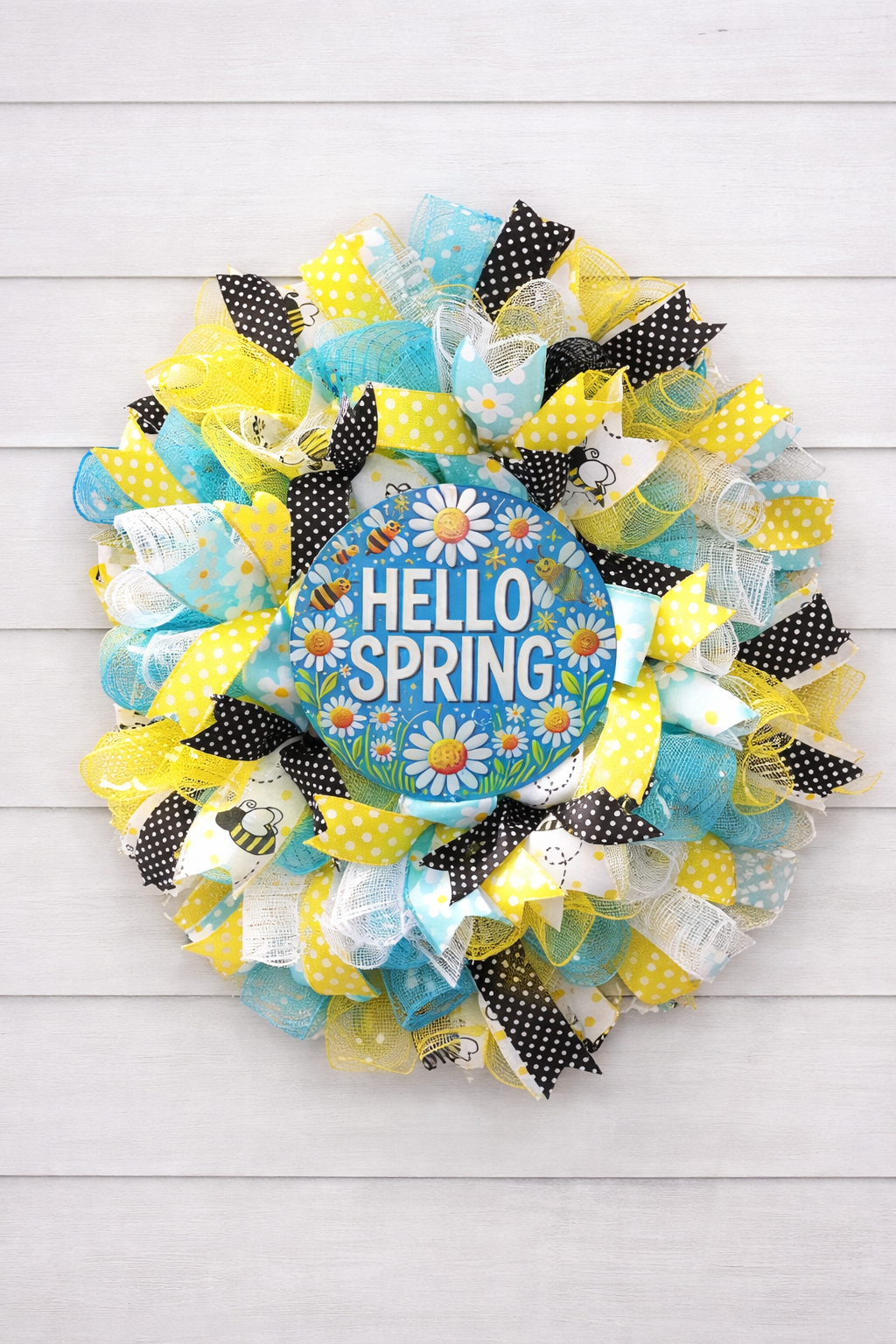 Decorative wreath with 'Hello Spring' sign on a white wooden background