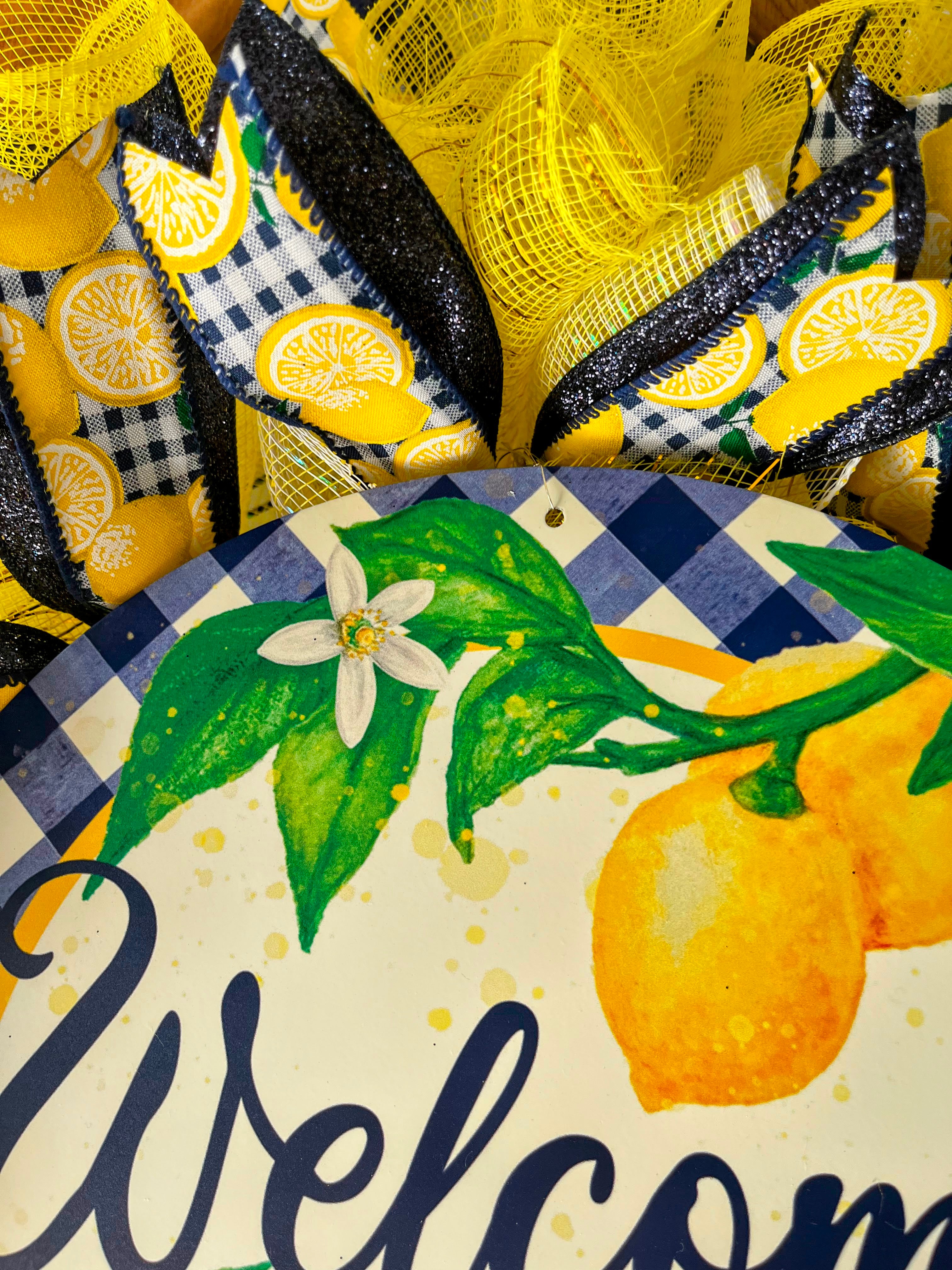 Handmade lemon wreath with bright yellow mesh and blue accents, featuring a ‘Welcome’ sign and citrus design for summer farmhouse front door decor.