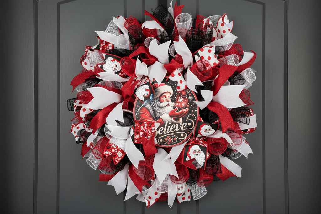 Decorative Santa Clause deco mesh Christmas wreath with red, white, and black ribbons on a plain background