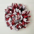 Handmade Christmas deco wreath with red, white, and black ribbons and Santa Claus "Believe" centerpiece.