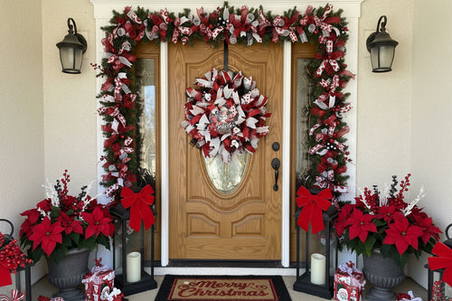 Decorative wreath with red, white, and black ribbons on a wooden door.