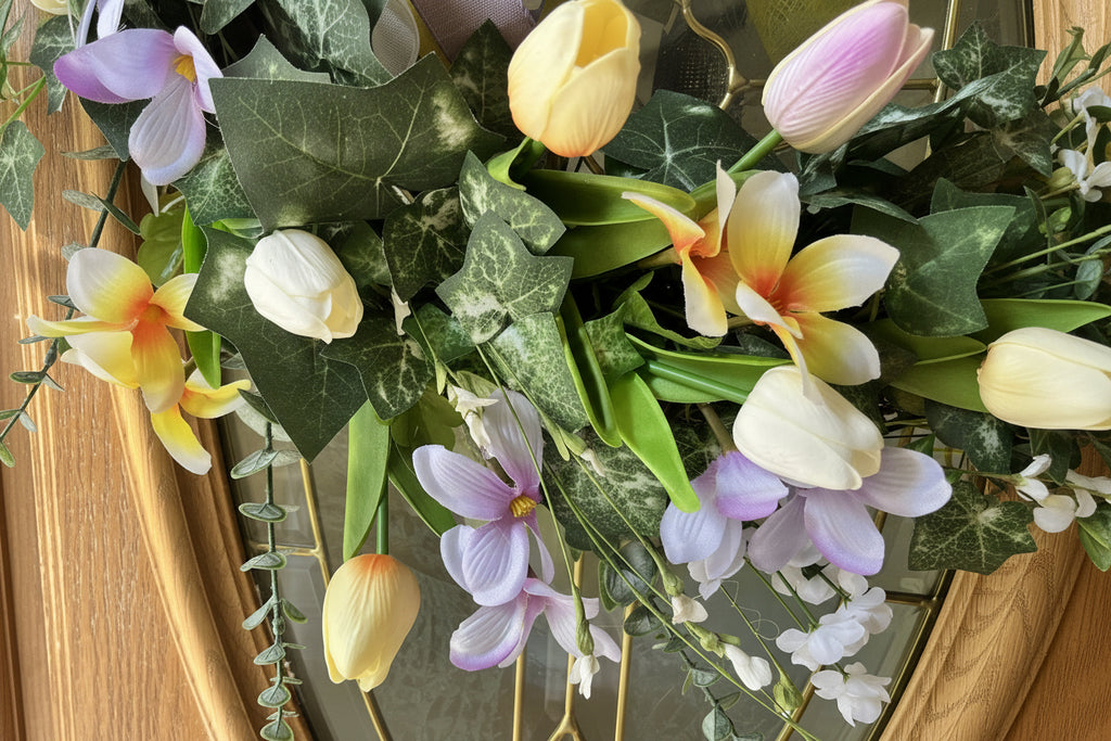 Handmade spring wreath with pastel tulips and florals in lavender, yellow, and white, featuring greenery and a decorative bow for front door decor.