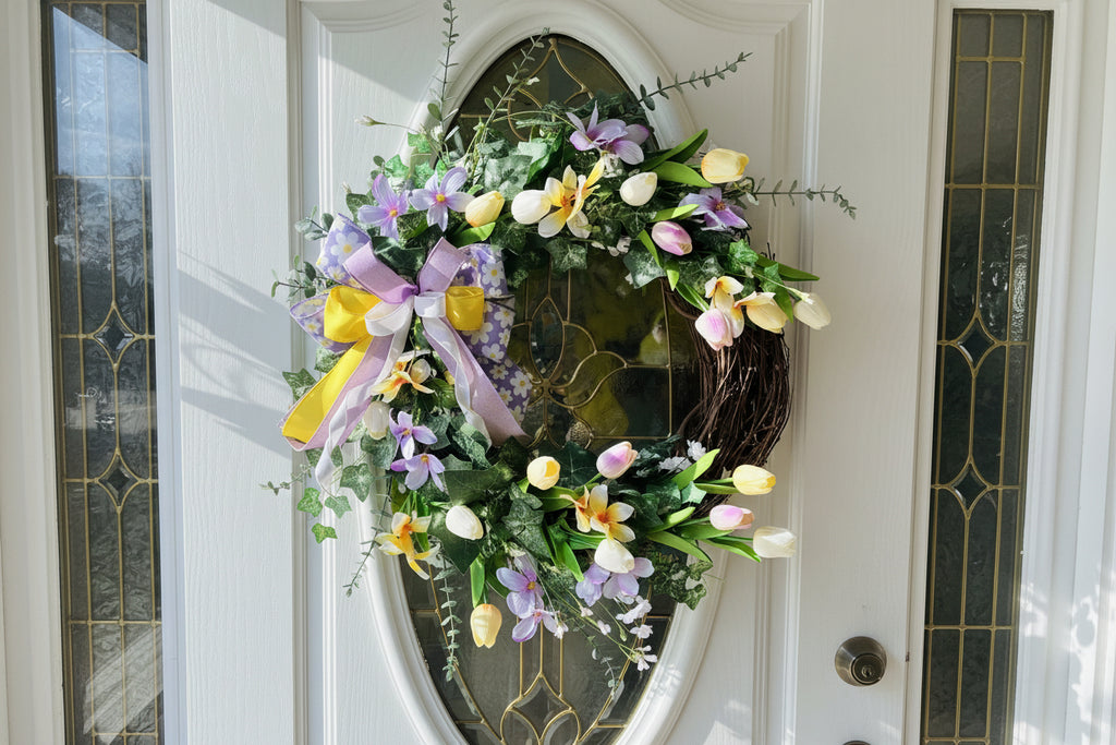 Handmade spring wreath with pastel tulips and florals in lavender, yellow, and white, featuring greenery and a decorative bow for front door decor.