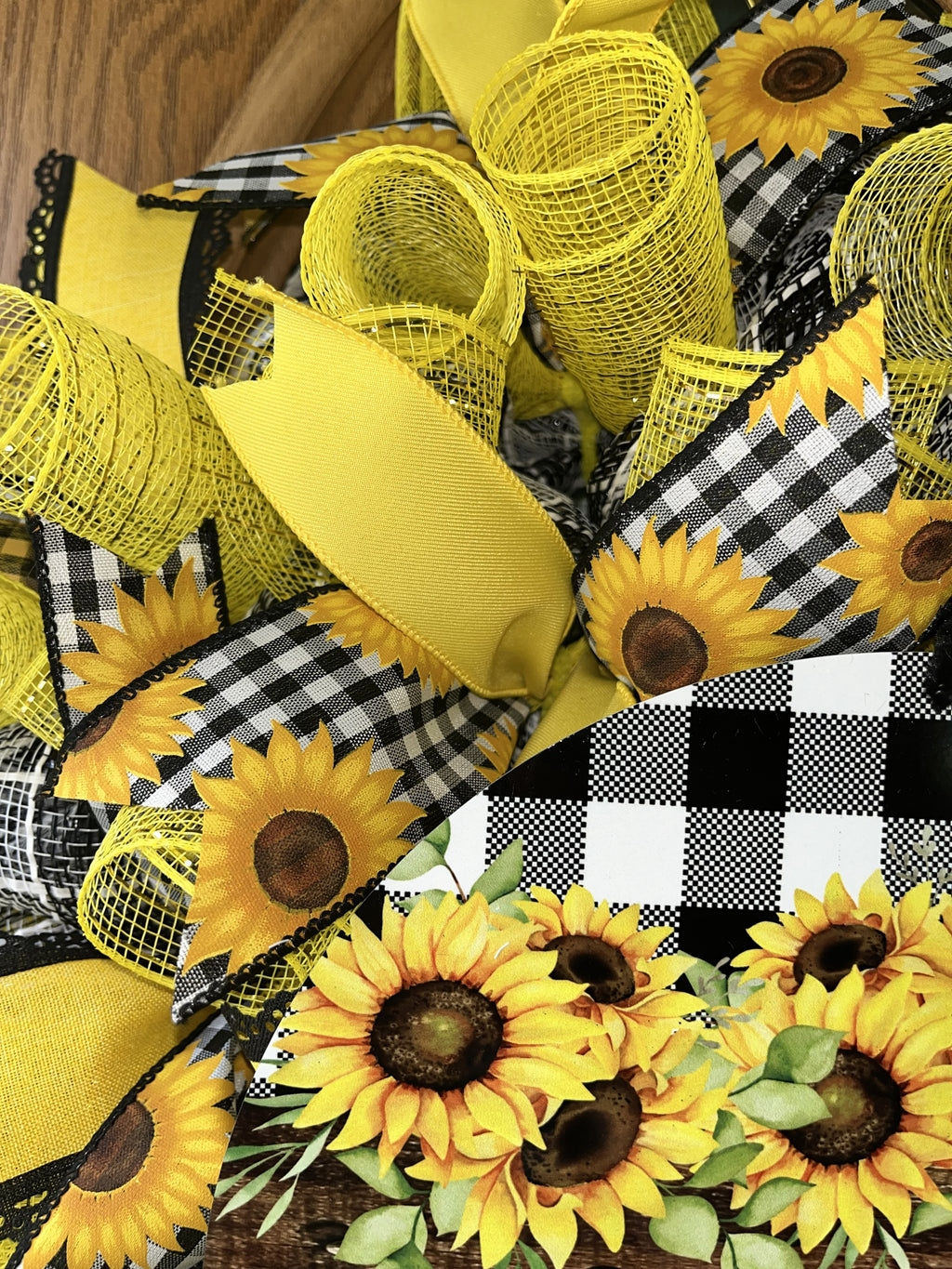 Handmade sunflower wreath with black and white buffalo check ribbon and a welcome sign, featuring bright yellow sunflowers for farmhouse front door decor.