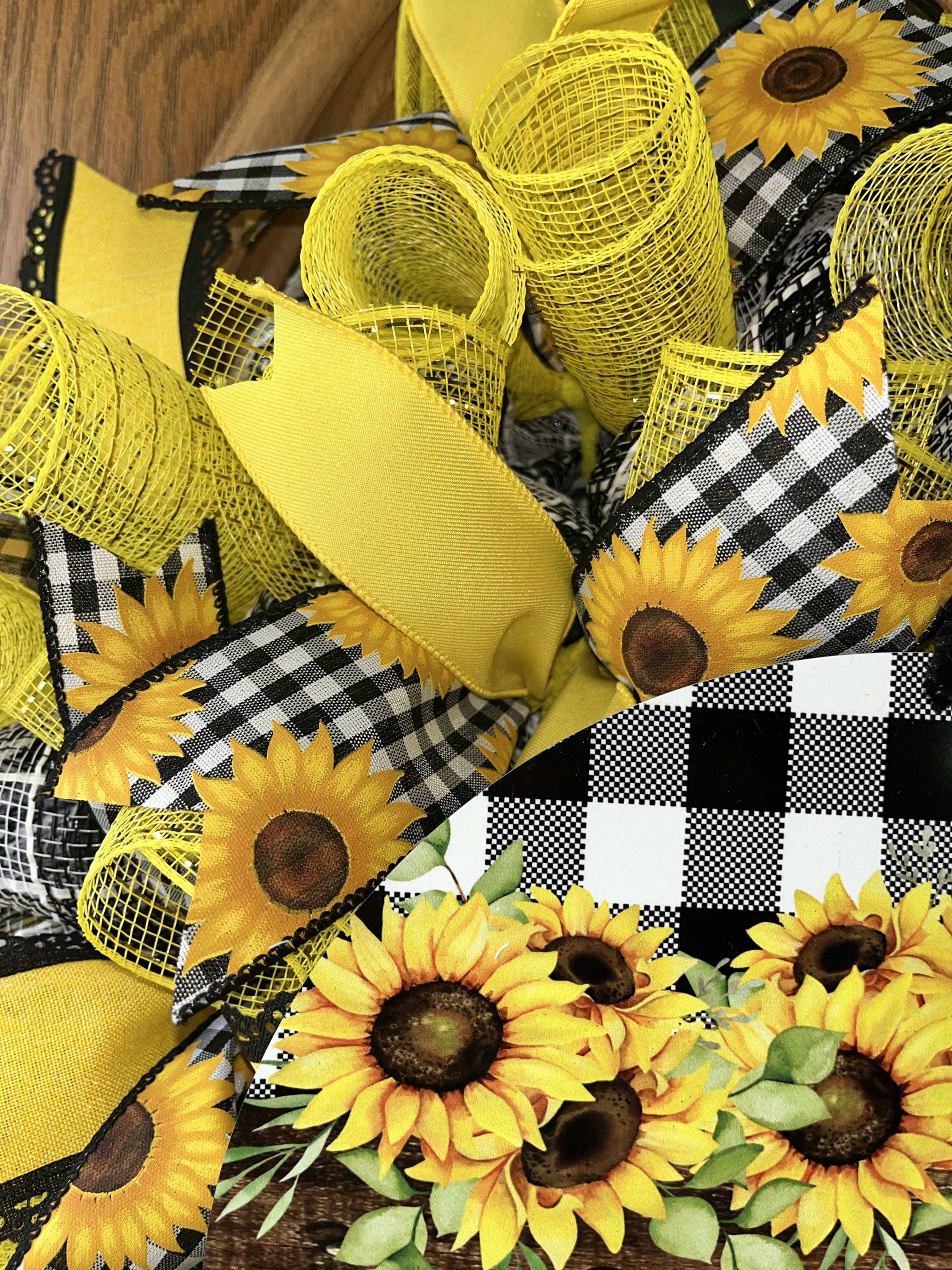 Handmade sunflower wreath with black and white buffalo check ribbon and a welcome sign, featuring bright yellow sunflowers for farmhouse front door decor.