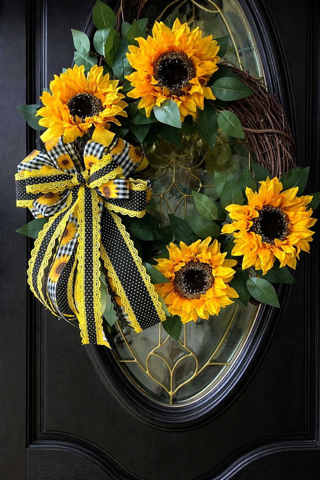 Handmade sunflower wreath with bright yellow sunflowers, greenery, and a black and yellow buffalo check bow for farmhouse summer front door decor.