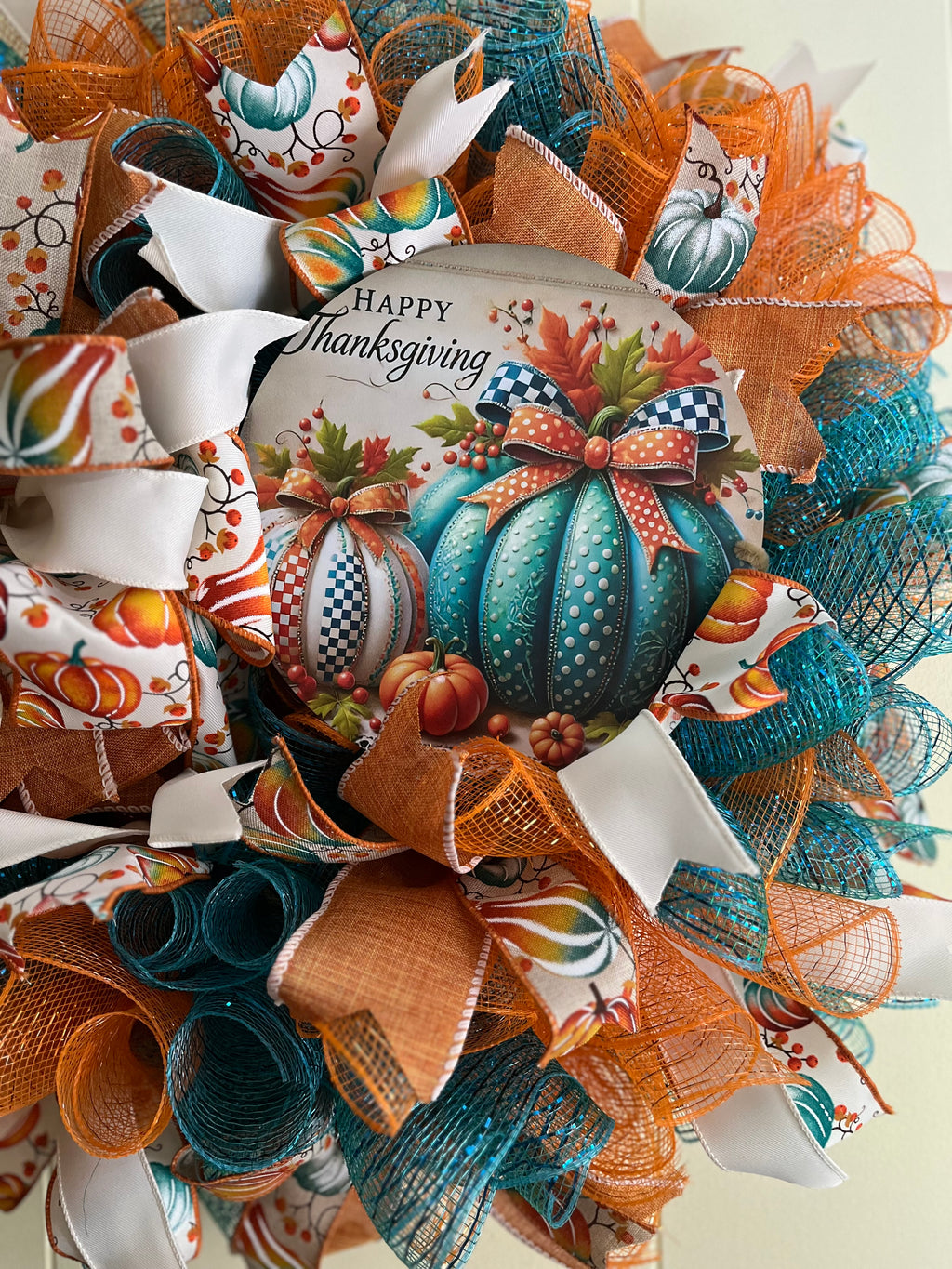 Handmade rustic teal and orange fall wreath with pumpkins and 'Happy Thanksgiving' text on a cream background