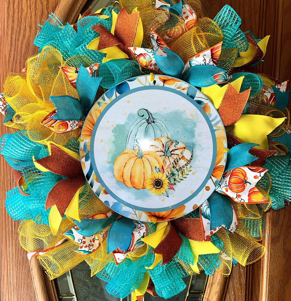 Handmade fall wreath featuring teal, yellow, and orange mesh with a pumpkin sign, perfect for unique autumn front door decor.