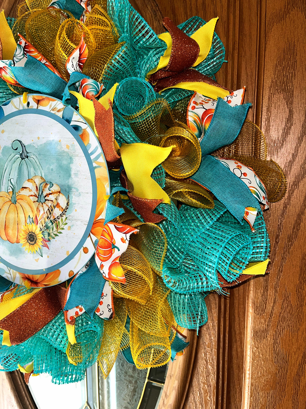 Handmade fall wreath featuring teal, yellow, and orange mesh with a pumpkin sign, perfect for unique autumn front door decor.