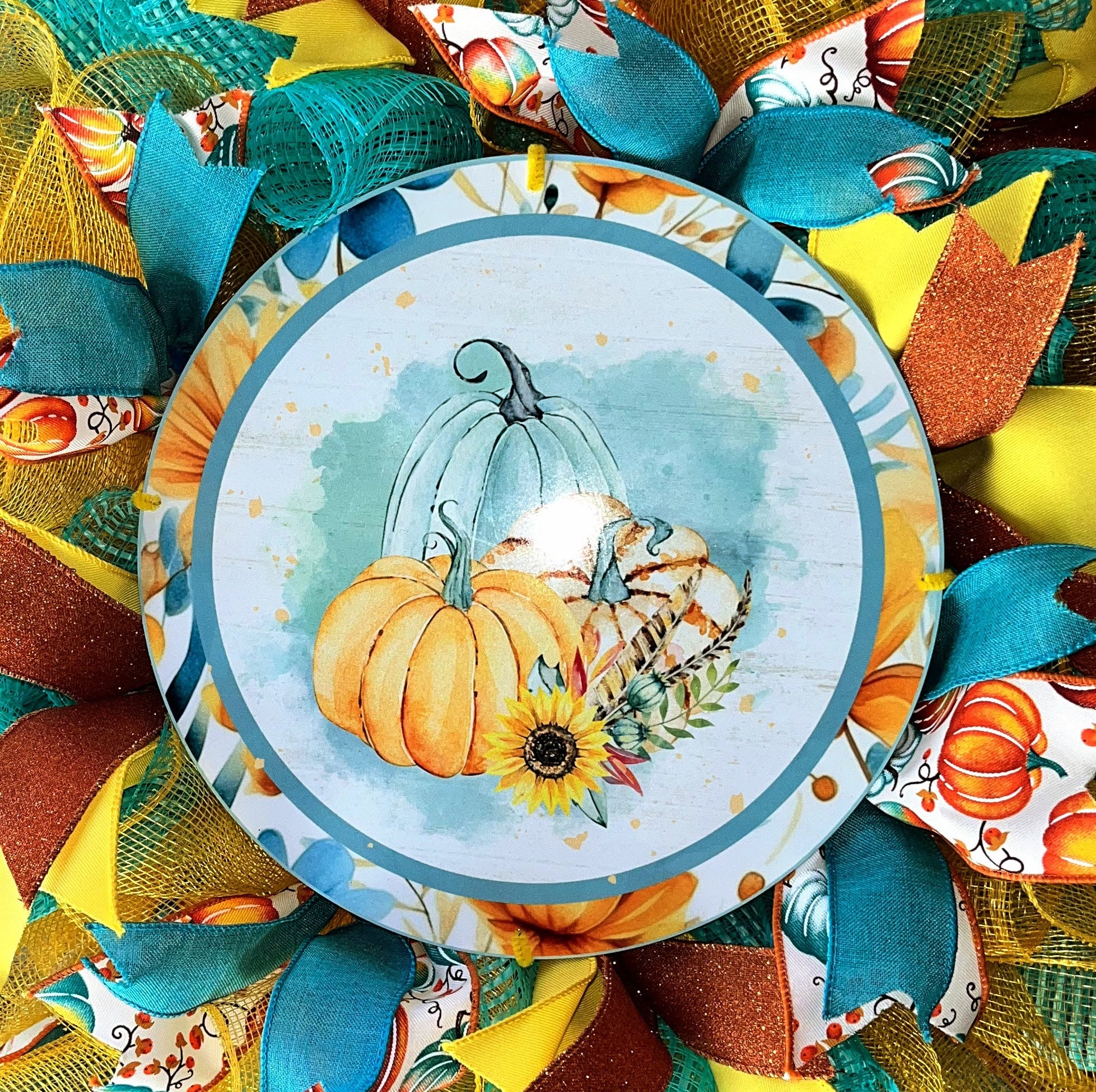 Handmade fall wreath featuring teal, yellow, and orange mesh with a pumpkin sign, perfect for unique autumn front door decor.