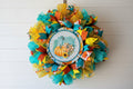 Handmade fall wreath featuring teal, yellow, and orange mesh with a pumpkin sign, perfect for unique autumn front door decor.